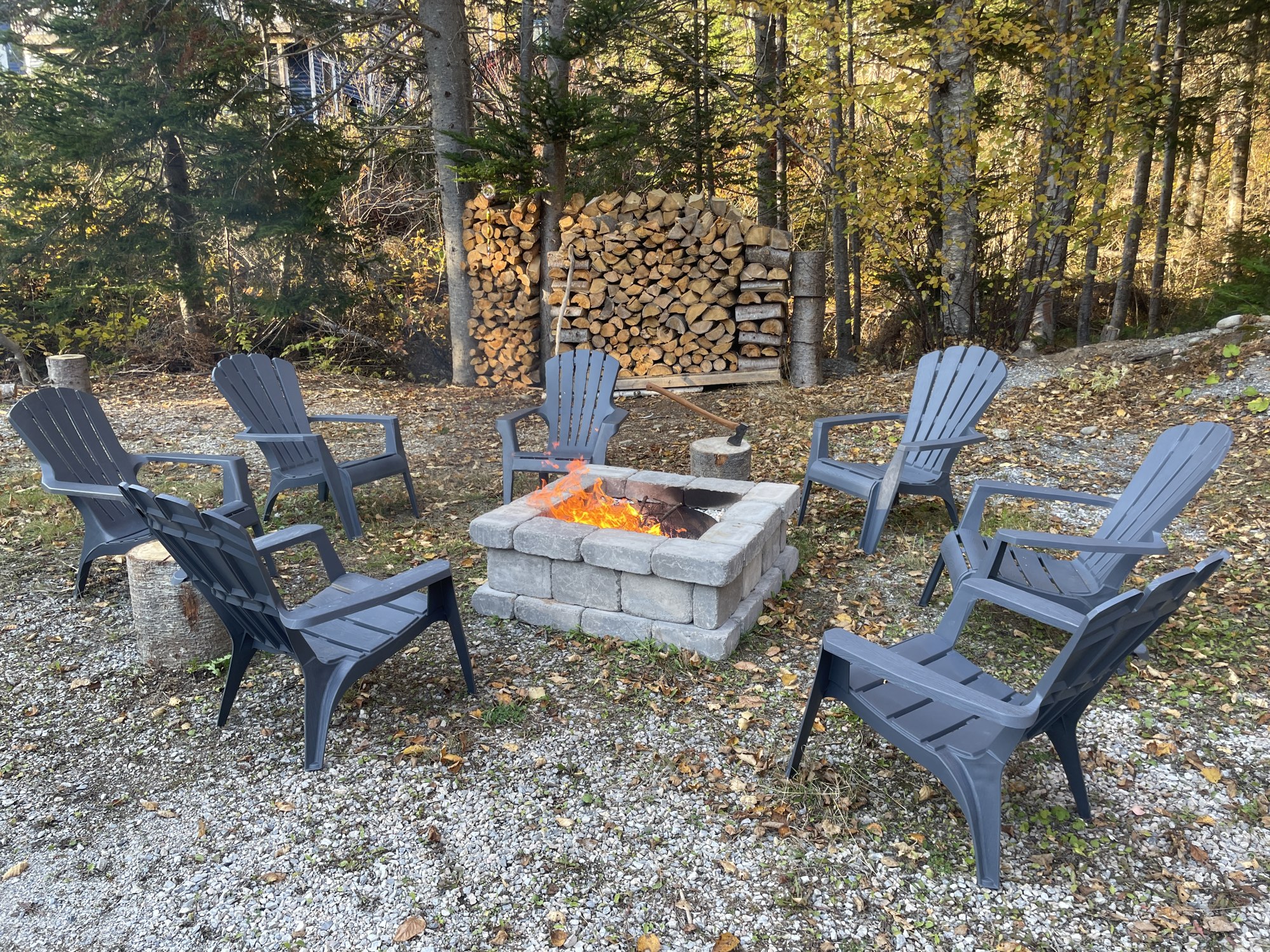 Outdoor firepit and Adirondack chairs among autumn trees